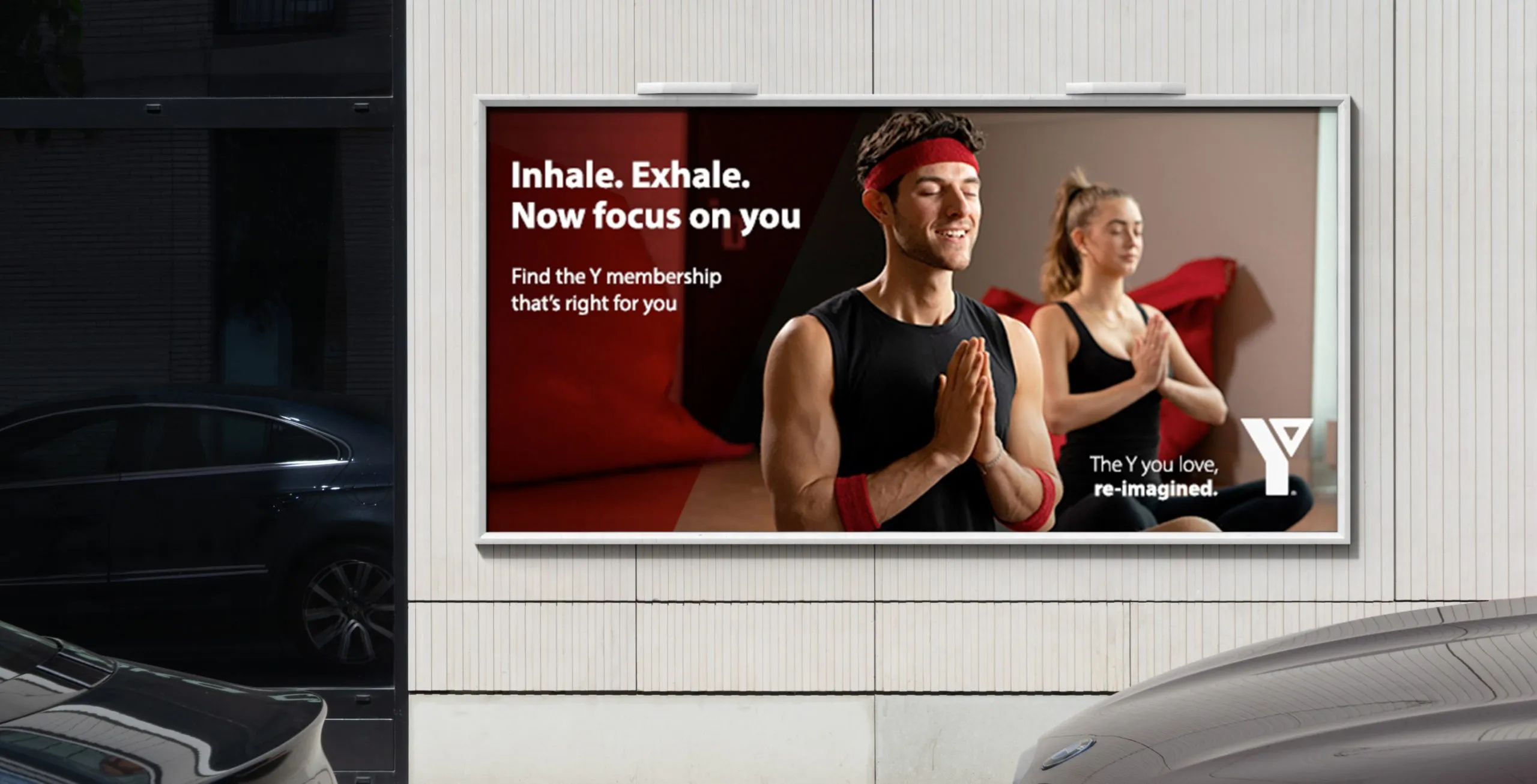 a parking garage with 2 car and a ad for the YMCA